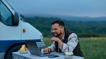 Camping with laptop outdoors in scenic landscape.