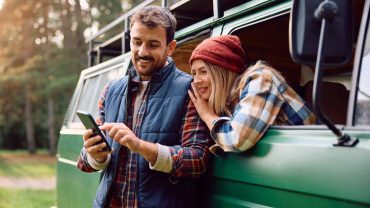 Outdoor adventure with a couple using a smartphone in a campervan.