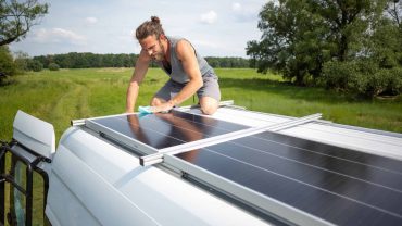 Solar panel installation on a caravan roof in a rural setting.