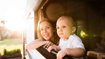 Happy mother and child looking out of a window at sunset.