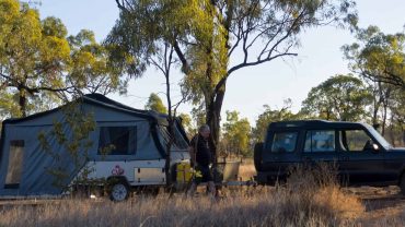 Camping setup with caravan and vehicle in the Australian bush.