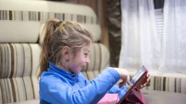 Young girl using a tablet with Big Lap Bible app at home.