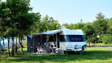 Camping caravan with outdoor setup in a lush green park.