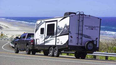 RV towing a caravan along scenic coastal highway.