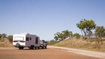 RV towing a caravan on a rural Australian road.