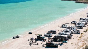 Beach camping with caravans and tents on the coast.