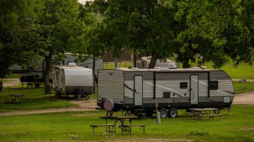 Camping RV at Big Lap Bible site, Australia, with picnic tables and lush green trees.