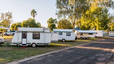 Camping car park with multiple caravans at Big Lap Bible, Australia, surrounded by trees and clear s.