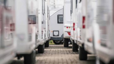 Row of motorhomes parked in a caravan park, ready for travel.