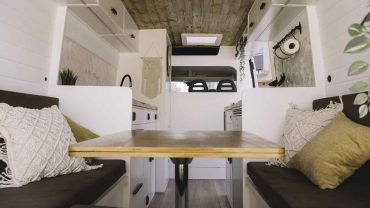 Interior of a cozy RV with a wooden dining table and comfortable seating.