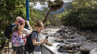 Hiking group exploring a river in lush forest scenery.