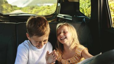 Family children enjoying a road trip in the backseat of a car.