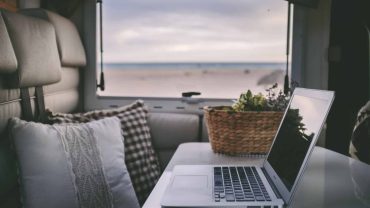 Cozy van interior with laptop and ocean view for travel and adventure.