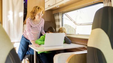Family traveling in a campervan with children working on a laptop.
