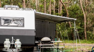 Solar panels and outdoor kitchen setup at a campsite in a wooded area.