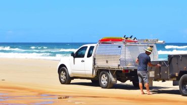 Rescue vehicle on the beach with a person preparing equipment near the ocean.