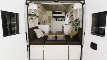 Interior view of a cozy camper van with seating and a dining area.