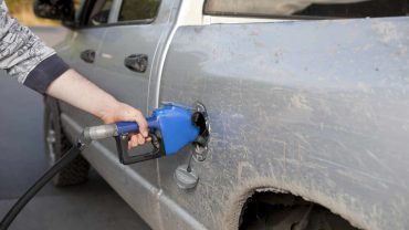 Person cleaning a muddy car with a pressure washer.