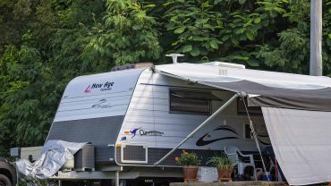 Caravan with awning set up in a lush green outdoor setting.